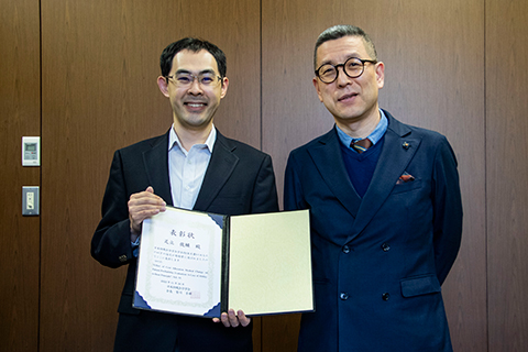 韓学長（写真右）に笑顔で受賞をご報告する足立先生（写真左）